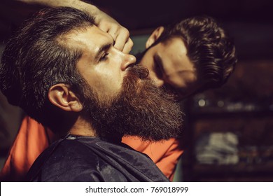 Handsome Bearded Man, Hipster, Brunette With Beard And Moustache Has Haircut Or Clippering In Hairdressing Saloon. Barber Works In Barbershop