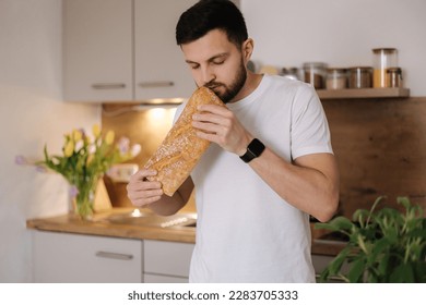 Handsome bearded man smell a freshly baked baguette. Home food concept  - Powered by Shutterstock