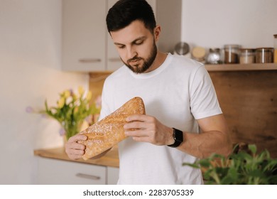 Handsome bearded man smell a freshly baked baguette. Home food concept  - Powered by Shutterstock