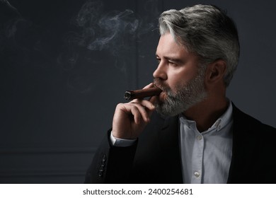 Handsome bearded man smoking cigar against dark grey background. Space for text - Powered by Shutterstock