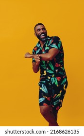 Handsome Bearded Mid Adult African American Man Smiling And Dancing Wearing Hawaiian Shorts And Shirt On Vacation Studio Shot