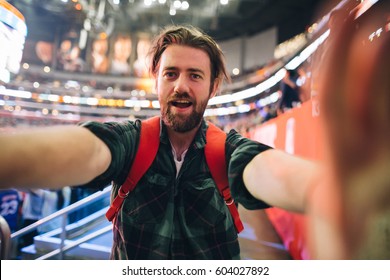 Handsome Bearded Supporter Watching Basketball Game And Making Selfie Self-portrait With Smartphone At Stadium