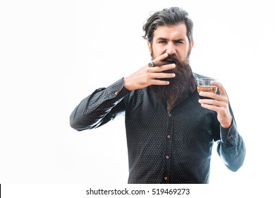 handsome bearded tough rich man with stylish hair mustache and long beard on serious face in blue fashion shirt smoking cigar and holding glass of whiskey isolated on white, copy space