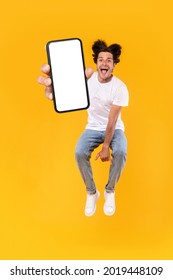 Handsome bearded young man recommending new mobile application, vertical collage. Excited guy holding smartphone, showing white blank screen, jumping up over orange yellow studio background