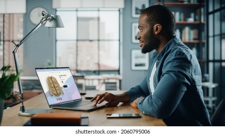 Handsome Black African American Man Is Using Laptop Computer With Clothing Online Web Store To Choose And Buy Clothes For New Fresh Look. Beautiful Man Surfing The Internet At Home Living Room.