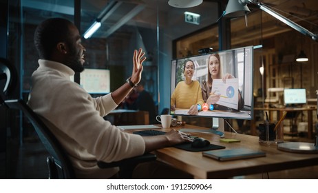 Handsome Black African American Project Manager Is Making A Video Call On Desktop Computer In A Creative Office Environment. Male Specialist Talking To A Two Female Colleagues Over A Live Camera.