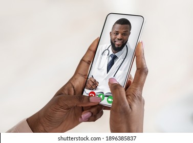 Handsome black doctor consulting female patient remotely by video call on smartphone. Unrecognizable woman getting online consultation via web conference with her therapist, creative collage, closeup - Powered by Shutterstock