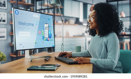 Handsome Black Female Is Using Desktop Computer That Shows Welcome Page Of A Popular Social Network. Freelance Woman Working Over The Internet As A Social Network Marketer.