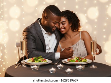 Handsome black man embracing his beautiful woman while festive dinner at restaurant, St. Valentine's Day concept