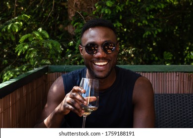 Handsome Black Man Holding Cup Of Wine And Smiling Widely At Camera Outdoors. Medium Shot. 