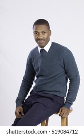 Handsome Black Man Sitting On A Stool And Smiling At The Camera