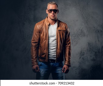 Handsome Blond, Muscular Male In Sunglasses, Dressed In A White T Shirt And Brown Leather Jacket.