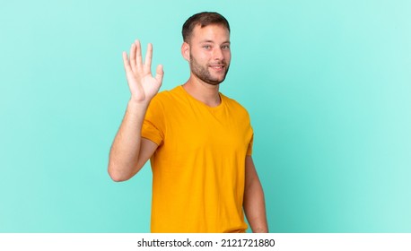 Handsome Blonde Man Smiling Happily, Waving Hand, Welcoming And Greeting You