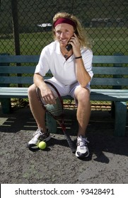 A Handsome Blonde Tennis Player Sits On The Sideline Bench And Talks On His Cell Phone