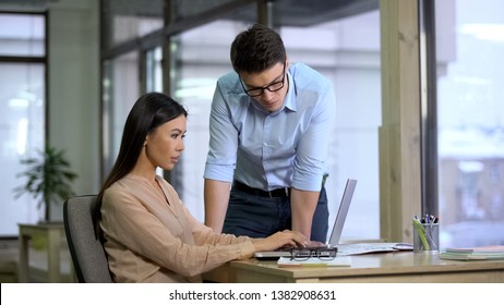 Handsome boss checking work of female assistant, journalists writing article - Shutterstock ID 1382908631