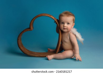 Handsome Boy Kid Lies In A Wooden Heart Looks At The Camera. High Quality Photo