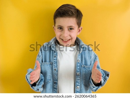 Handsome boy posing over yellow background gesturing with hands and showing big and large size sign, measure symbol. Looking at the camera with smile. Measuring concept.