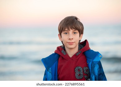 Handsome boy posing at the winter beach. Cute smiling happy 11 years old boy at seaside, looking at camera. Kid's outdoor portrait. - Powered by Shutterstock