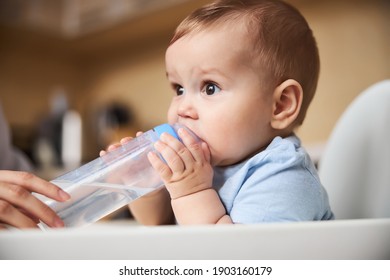 Handsome boy raising his eyebrows while drinking water, sitting in chair for babies - Powered by Shutterstock