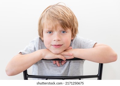 Handsome boy sitting on the chair chin on hands with blue eyes and beautiful smile - Powered by Shutterstock