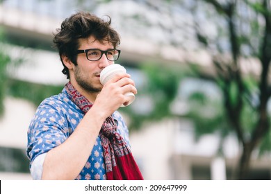 Handsome brunet drinking coffee in takeaway cup outdoors