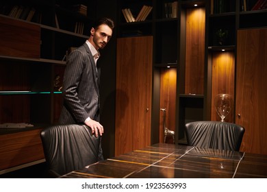 Handsome brunet man in an elegant suit man stands in a luxury office. Mafia. Male beauty, fashion.