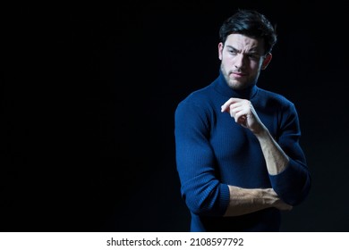 Handsome Brunet Man With Smile Posing Against Black Background With Copy Space. Posing In Blue Turtle NEck Sweater With Folded Hands As Successful Young Man.Horizontal Image