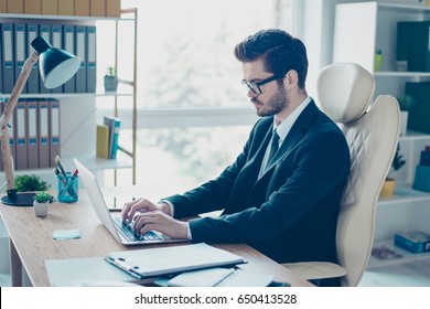 Handsome brunette young man is working in the modern office. He is typing on his laptop