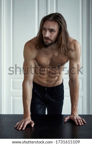 Handsome brutal man with beard and cool long hair.Sexy topless athletic body . Confident, attractive, stylish. Fashion shooting. Actor.