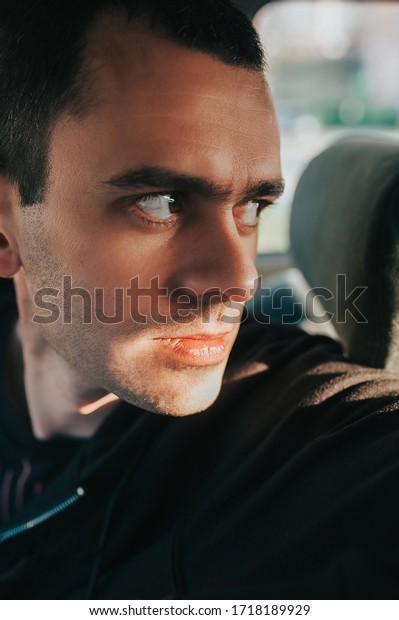 handsome brutal thin man\
with big brown eyes, clear skin, and rough stubble in a dark car\
and black clothes. bold portrait of a man close up. selective\
focus, mood toning