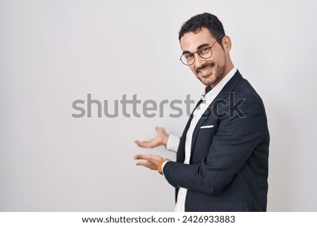 Handsome business hispanic man standing over white background inviting to enter smiling natural with open hand 