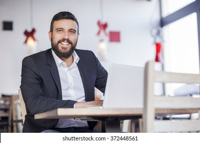 Handsome Business Man Working On Lap Top In Restaurant. Shallow Depth Of Field