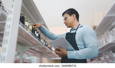 Handsome business owner or staff using computer tablet checking product inventory on shelf stock in grocery store - Powered by Shutterstock