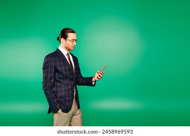 A handsome businessman in a chic suit holding a cell phone in front of a green screen. - Powered by Shutterstock