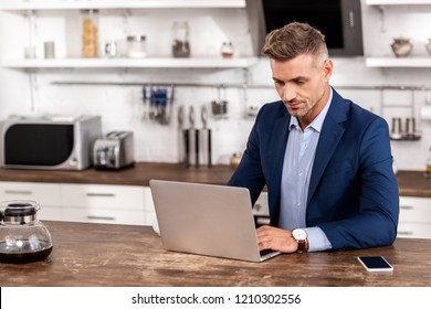 gut aussehender Geschäftsmann mit Laptop zu Hause