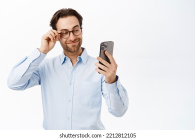 Handsome Businessman In Glasses, Using His Mobile Phone, Working On Smartphone App, Standing In Blue Collar Shirt Over White Background