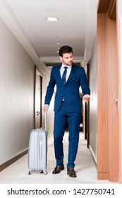 handsome businessman holding hotel card while standing with suitcase  - Shutterstock ID 1427750741
