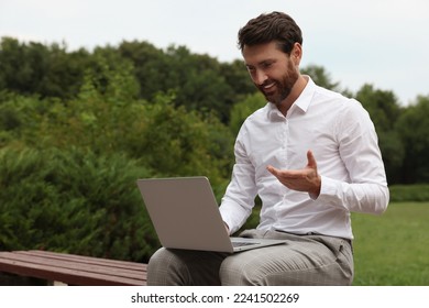 Handsome businessman with laptop on bench in park - Shutterstock ID 2241502269