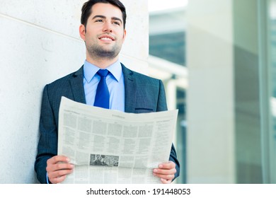 Ein ansprechender Geschäftsmann oder Manager, vor der modernen Büroarchitektur, Zeitungslesen