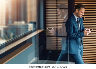 Handsome businessman with mobile phone in the office.Smiling man holding cellphone ,ordering delivery online or texting.