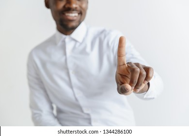 Handsome businessman pointing his finger to the camera and slicking virtual image or text, finger is in focus while his face is out of focus. Shallow depth of field. Young african american guy