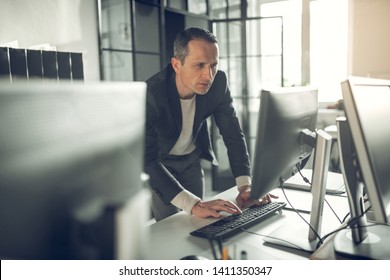 Handsome businessman. Handsome prosperous businessman typing e-mail for business partner while using computer