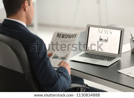 Handsome businessman reading financial newspaper in office