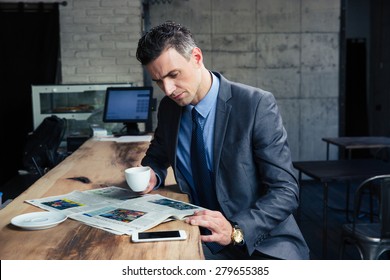 Handsome businessman reading magazine and drinking coffee in cafe - Powered by Shutterstock