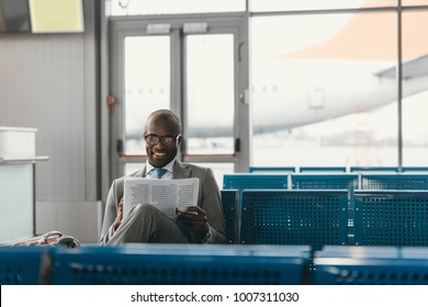 handsome businessman reading newspaper while waiting for flight at airport lobby - Powered by Shutterstock