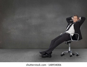 Handsome Businessman Resting In His Swivel Chair In A Grey Empty Room