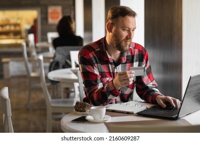 Handsome Businessman Shopping Online With Credit Card Using Laptop In Cafe, Young Man Sitting In Cafe While Using Laptop Computer And Holding Debit Card.