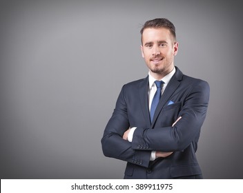 Handsome businessman standing with arms crossed on grey background