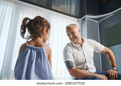 Handsome Businessman, Successful Entrepreneur, Loving Father Smiles, Sitting On The Table Face To His Beloved Cute Little Daughter, Paying Attention To Her Despite A Busy Work Schedule