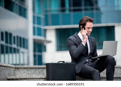 Handsome businessman in suit, talking on his phone and sitting outdoor - Shutterstock ID 1689350191